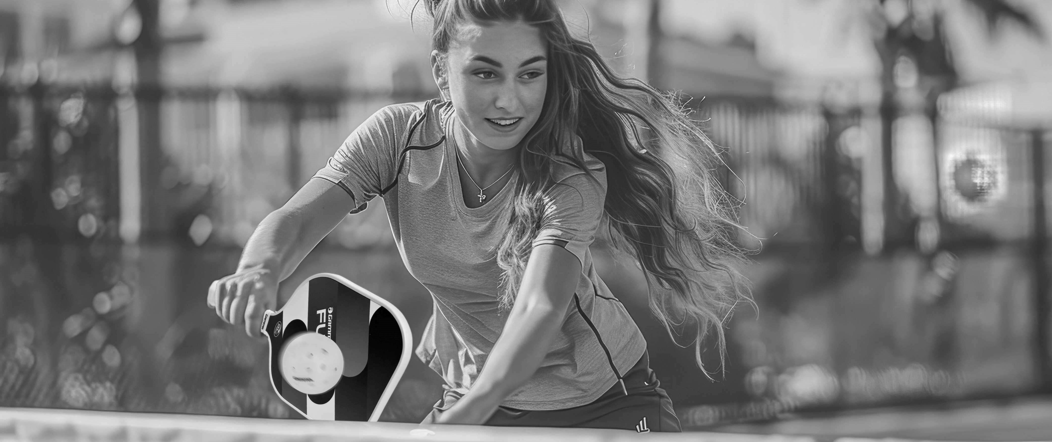 Junge Frau spielt Pickleball auf einem Außencourt Junge Frau spielt Pickleball auf einem Außencourt